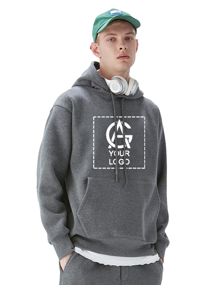 Young man wearing a solid color 350GSM hoodie with a placeholder logo, green cap, and gray sweatpants. He has plush white headphones around his neck and stands against a plain white background.