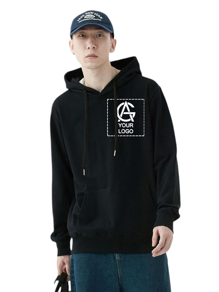 A young man wearing a navy blue cap and a unisex pullover hoodie with a "Your Logo" graphic on the chest, along with blue jeans, stands facing forward, holding a bag by his side against a plain white background.