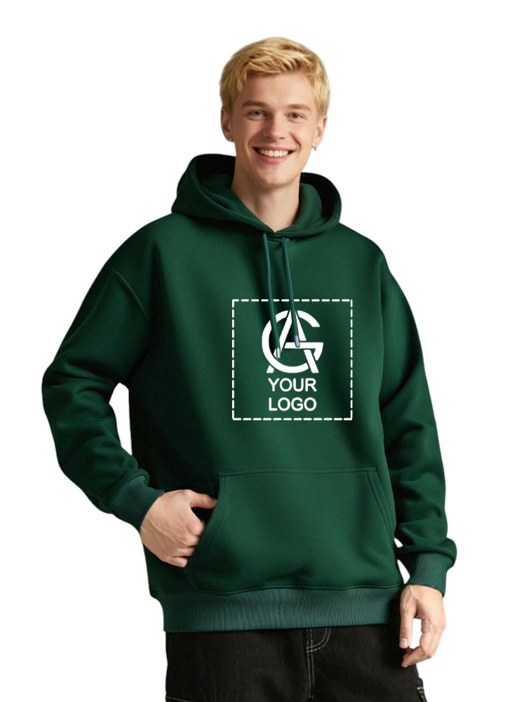 Smiling young person wearing a dark green Unisex Pullover Hoodie, 350GSM, with a blank customizable logo design on the front, one hand in the pocket and the other relaxed by their side.