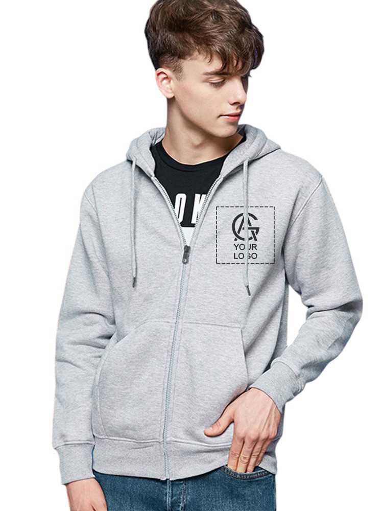 A young man wearing a light gray zip-up hoodie with a hood and front pockets, over a black T-shirt. The hoodie has a printed logo on the left chest. He is looking down and to the side.