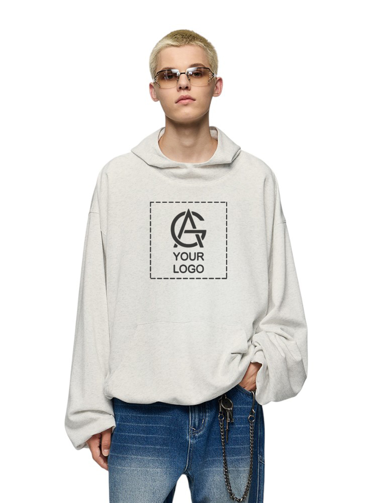 A person with short blond hair and sunglasses wears an oversized light gray hoodie displaying a placeholder logo and the words “YOUR LOGO,” paired with blue jeans and a chain accessory.