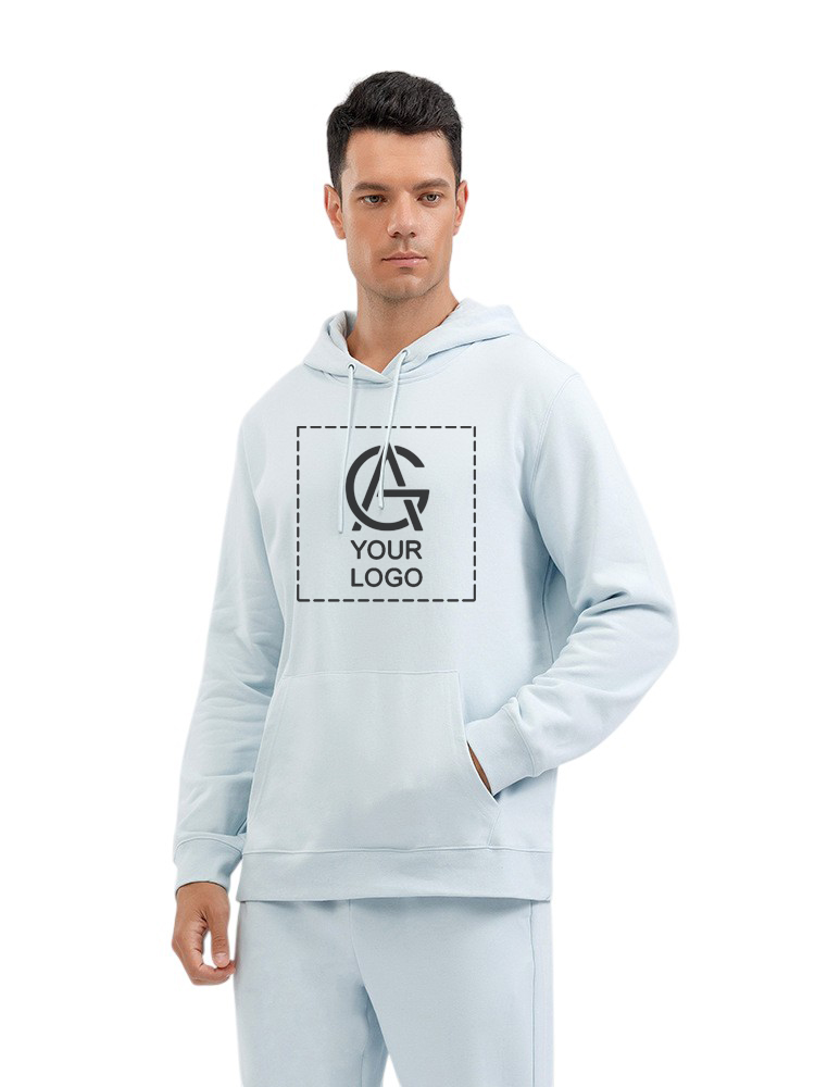 A man wearing a light blue hoodie and matching pants stands facing forward. The hoodie features a placeholder area with the words “YOUR LOGO” and a stylized logo within a dashed box on the chest.