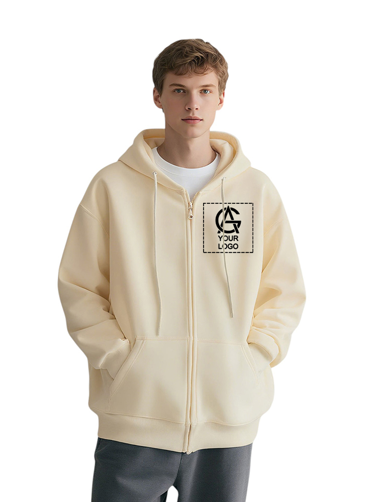 A young man wearing a light beige zip-up hoodie with a custom logo and "YOUR LOGO" text on the left chest, standing with hands in his pockets against a plain white background.