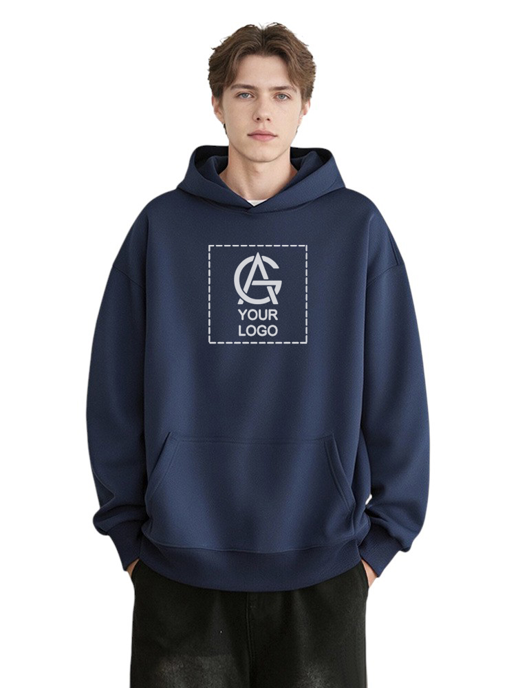 A young man wearing a dark blue hoodie with a blank logo space and the text "YOUR LOGO" on the front. He has short brown hair and stands with his hands in the hoodie pocket against a plain background.