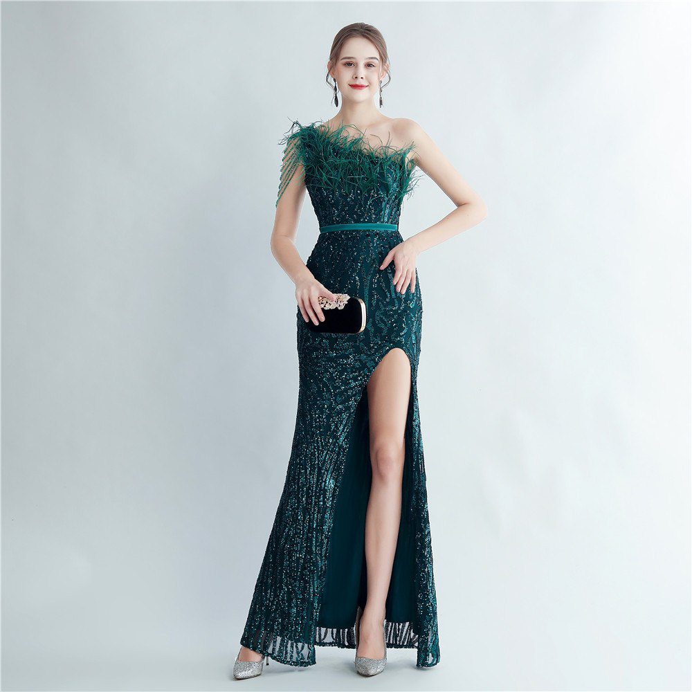 Model wearing an emerald green sequin evening gown with feather trim