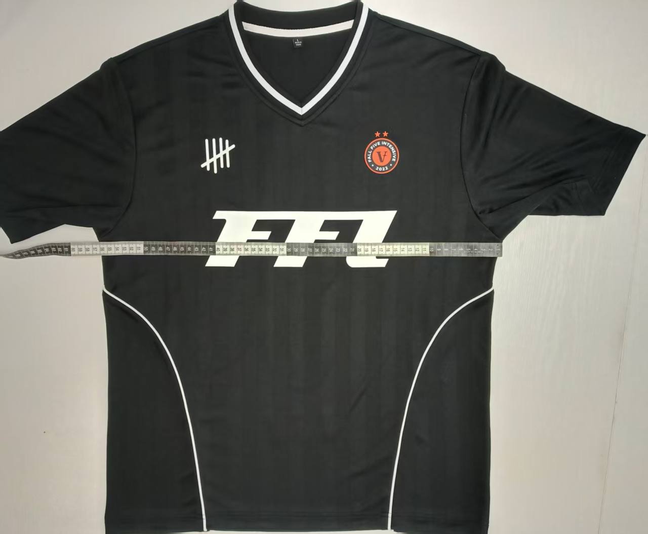 Front view of custom black jersey with logos during size inspection