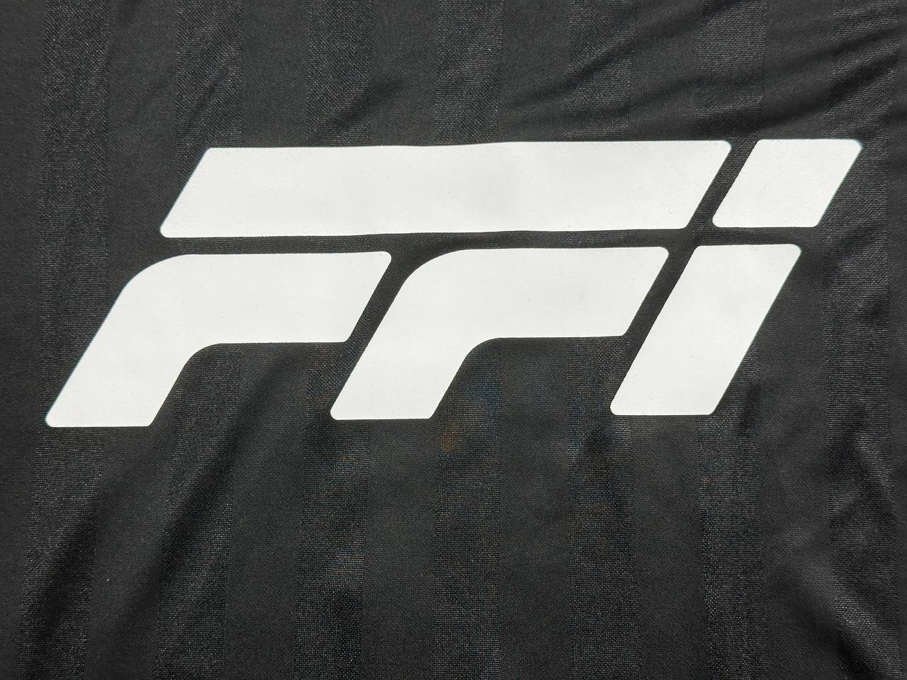 Close-up of white printed logo on black custom jersey