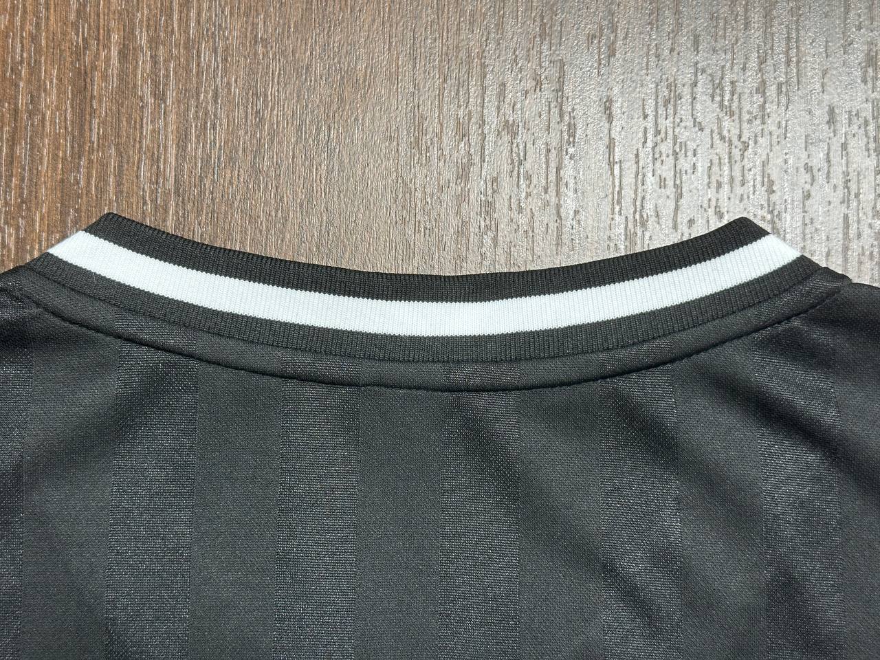 Close-up of black custom jersey with striped ribbed collar